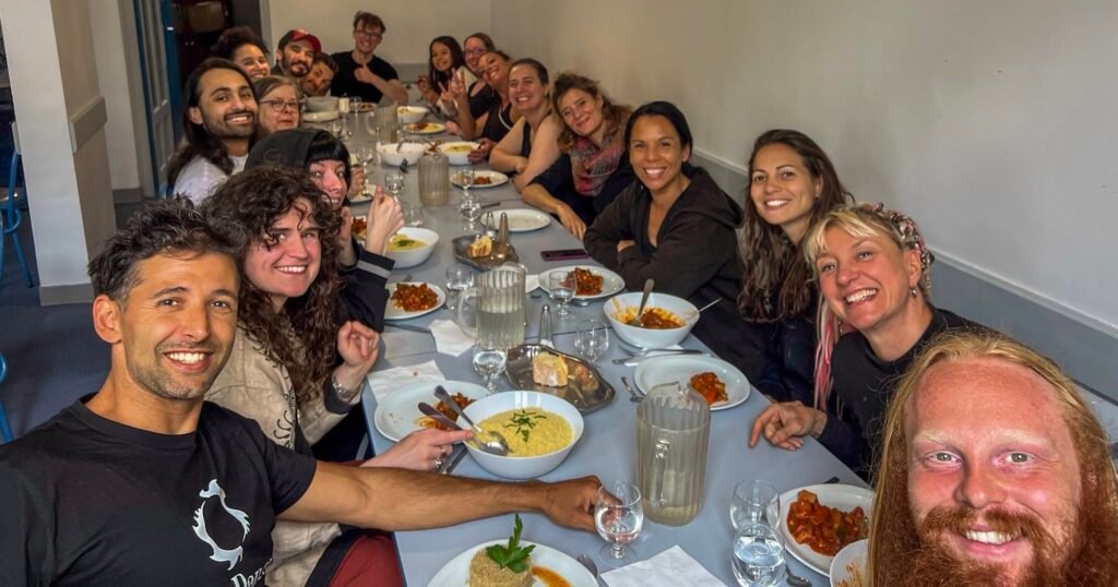 The 2025 Fire Dance Retreat group at a long dining table, smiling and looking happy.